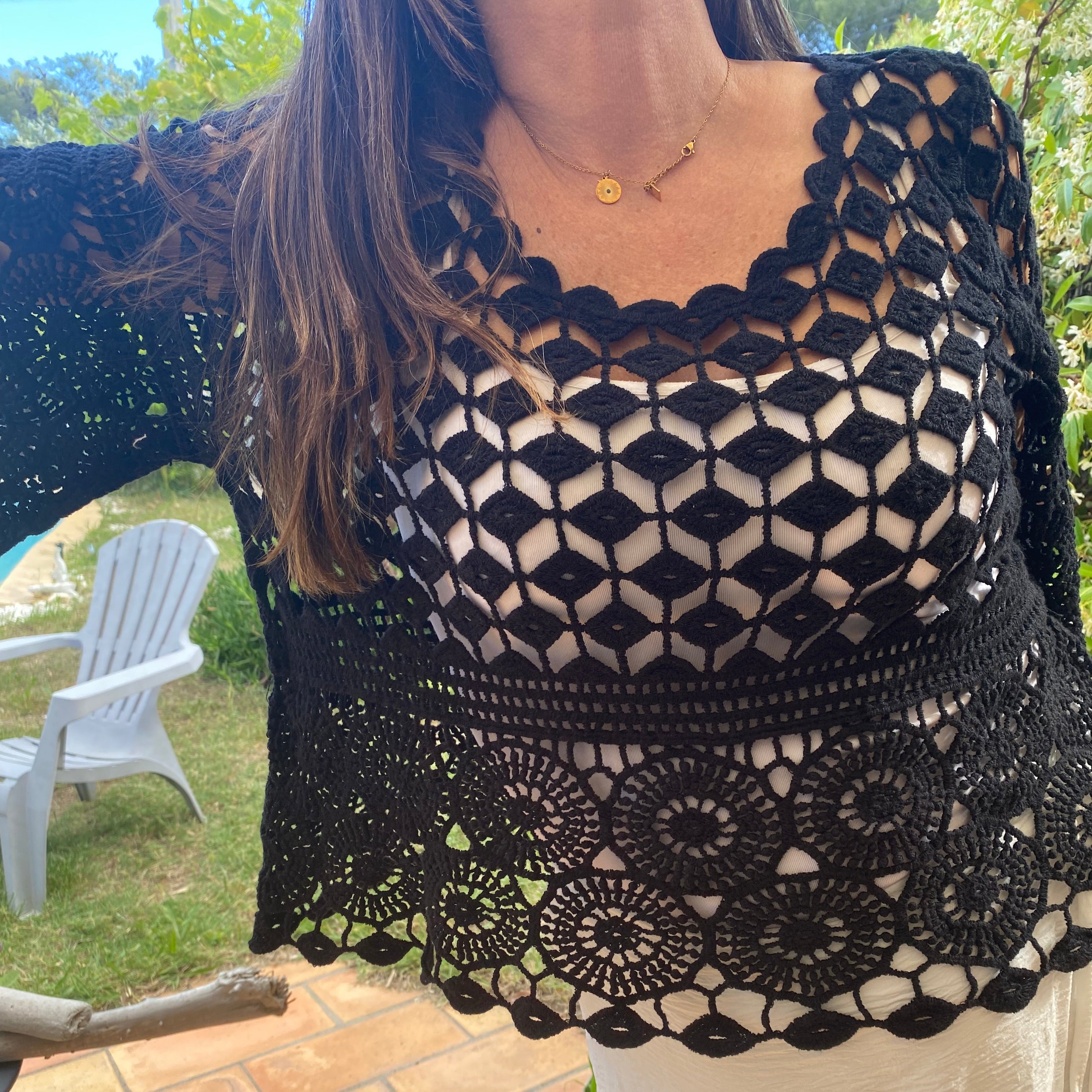 Top en crochet noir ajouré motif rsace sur le bas et damier au dessus de la poitrine. les manches sont de formes evasées sur et 3/4. il est porté sur une robe blanche à bretelle ce qui donne une jolie transparence . musthave et look boheme sur carry le rouet