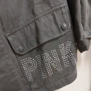 veritable veste mlitaire unie kaki . elle est customizée et on voit de près pink ecrit en majuscule et en petits clous sur toute la poche plaqué à revert avant gauche. sur carry le rouet