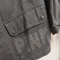 veritable veste mlitaire unie kaki . elle est customizée et on voit de près pink ecrit en majuscule et en petits clous sur toute la poche plaqué à revert avant gauche. sur carry le rouet