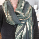 Femme portant le foulard CANA vert bouteille avec liseré or, écharpe élégante nouée autour du cou"