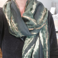 Femme portant le foulard CANA vert bouteille avec liseré or, écharpe élégante nouée autour du cou"
