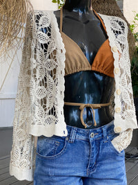 gilet en crochet blanc representant de belles fleurs. il est donc ajouré et manche longue et ferme a l'aide de 5 butons blancs sur sausset les pins