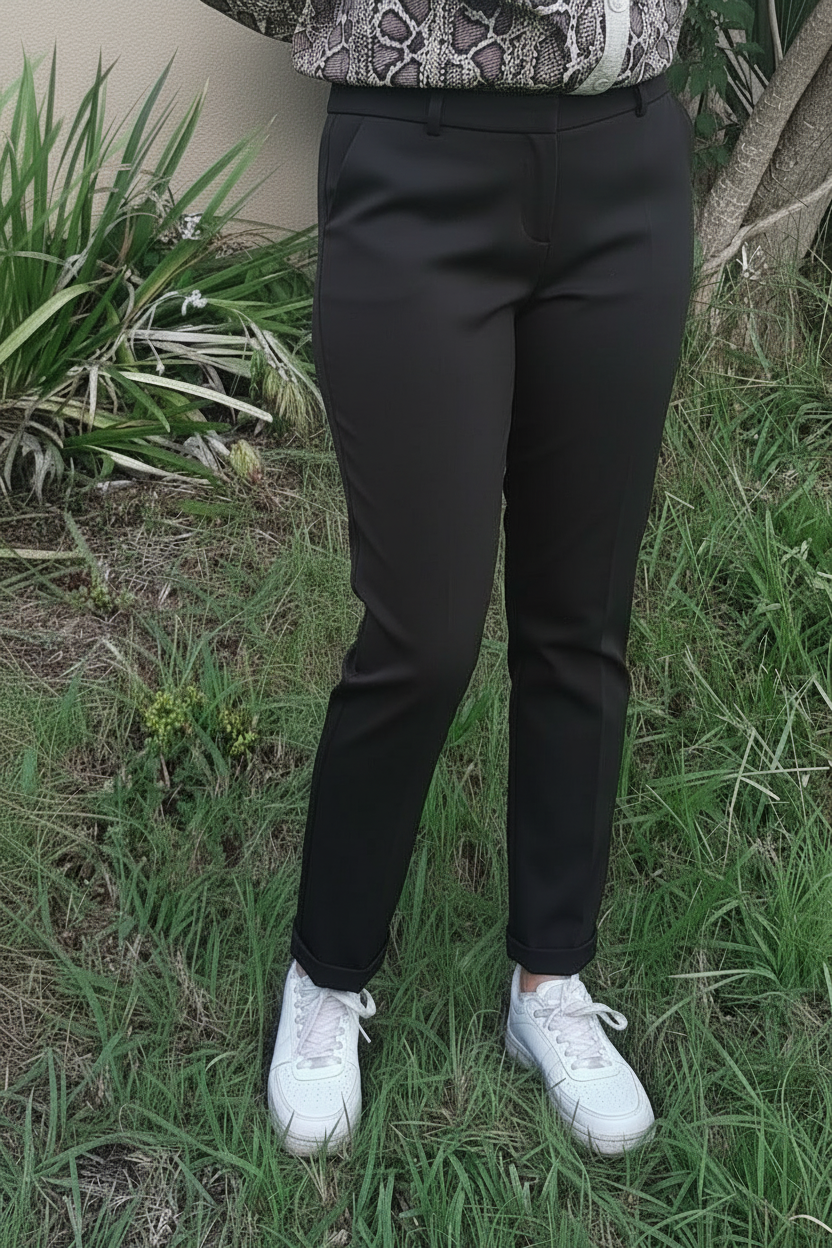 Pantalon city slim Cristiano noir porté face – coupe mi-haute stretch, revers bas, associé à une blouse python et sneakers blanches
