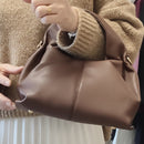 Femme portant le sac Byblos chocolat simili cuir grainé - forme bourse élégante et anse large confortable
